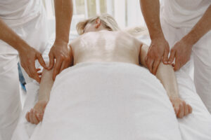 The massage with four hands. Concept of healthcare and female beauty. Two masseuses make a double  massage of a girl. Woman in a spa salon.